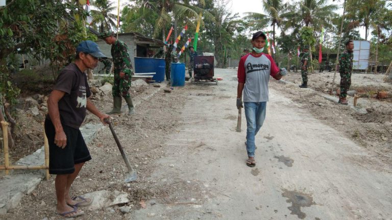 Dengan Menenteng Cangkul Arifudin Berjalan Penuh Semangat Ke Lokasi TMMD