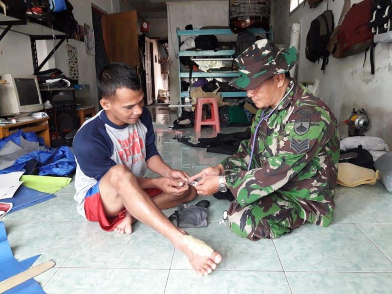 Dengan Cekatan Serka Darmanto Obati Kaki Warga Yang Terkena Serpihan Batu